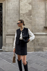 a lady in a white shirt, a black tweed vest and skirt two-piece set